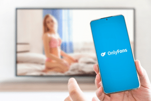 OnlyFans logo on mobile phone in the hands of sexy women