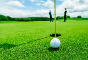 golf ball in the green grass close to the hole