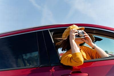 Young woman taking photos in the red car