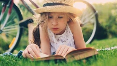 child reading book in summer