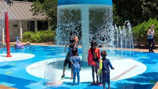 kids playing under water feature at spray grounds in Charlottesville