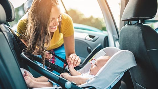 mom putting baby in carseat of vehicle