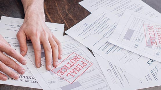 hands sorting past due bills on kitchen table