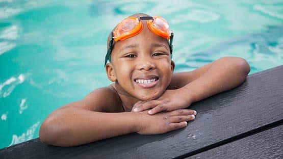 Black child smiling at pool edge