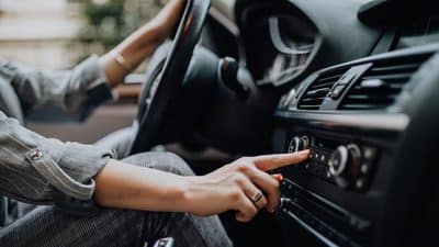 woman adjusting radio in car auto vehicle