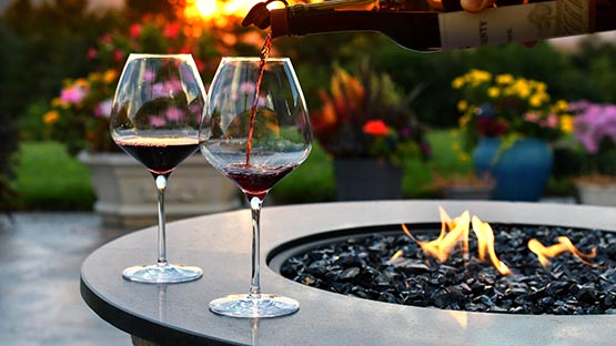 pouring wine on firepit on beautiful patio sunset