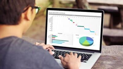 Person using Microsoft Excel on a laptop to review a project dashboard with charts, timelines, and workplace data.