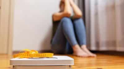 woman frustrated with weight scale measuring tape
